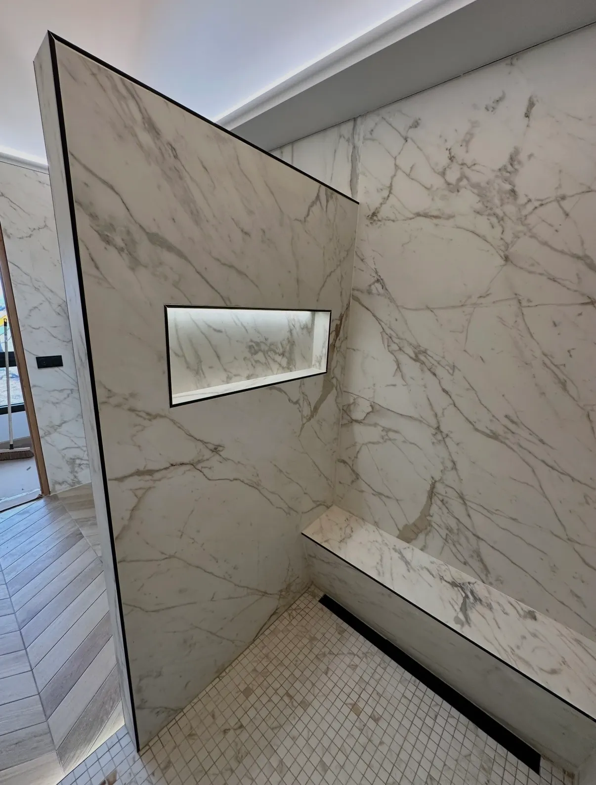 Douche habillée de grandes surfaces effet marbre avec niche murale éclairée