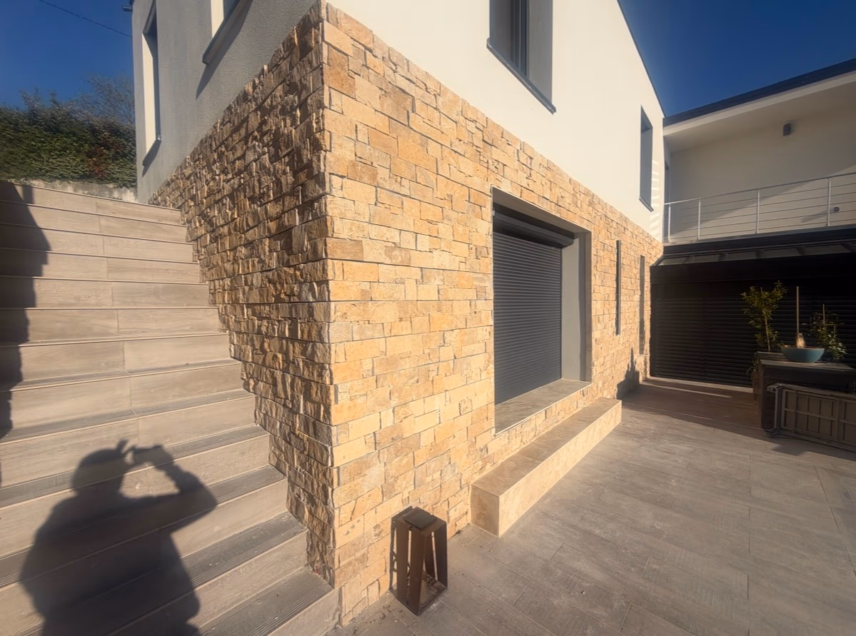 Parement en pierre sur une façade contemporaine avec escalier et sol extérieur carrelés