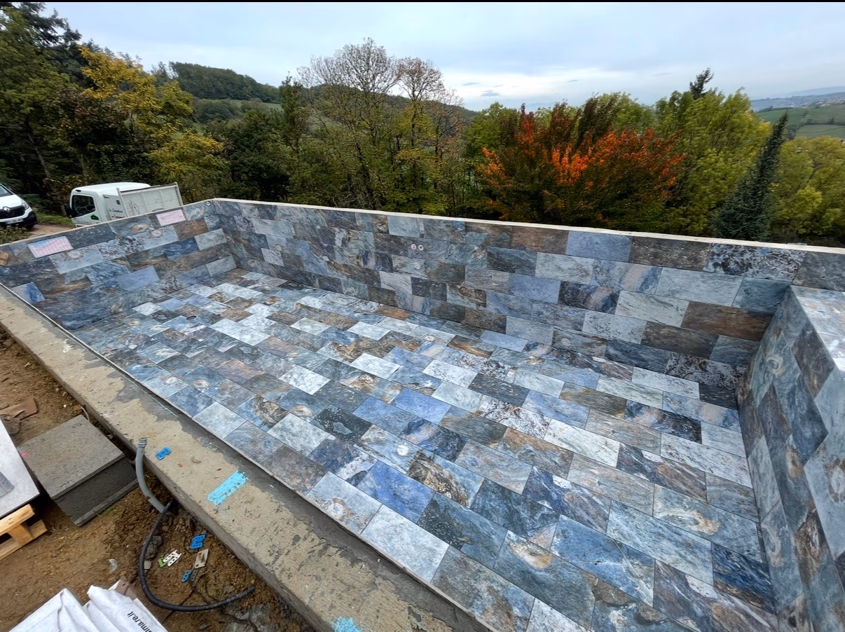 Piscine en cours de réalisation entièrement habillée de carreaux rectangulaires aux nuances de pierre bleue et grise