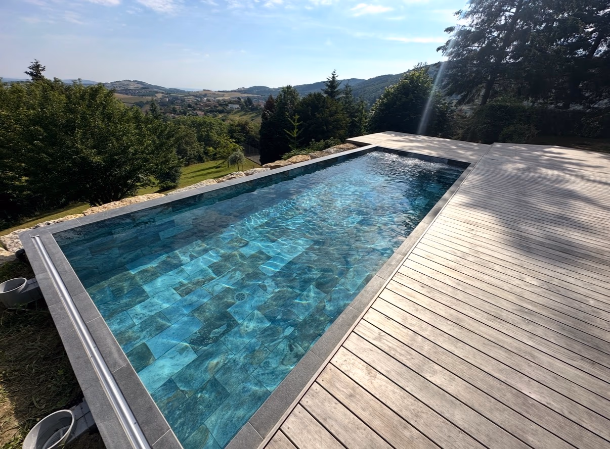 Piscine extérieure terminée avec revêtement minéral bleu et plage en bois