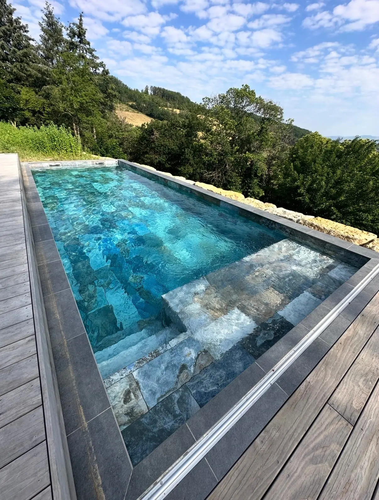 Piscine extérieure revêtue de carreaux aux nuances de pierre bleue et grise