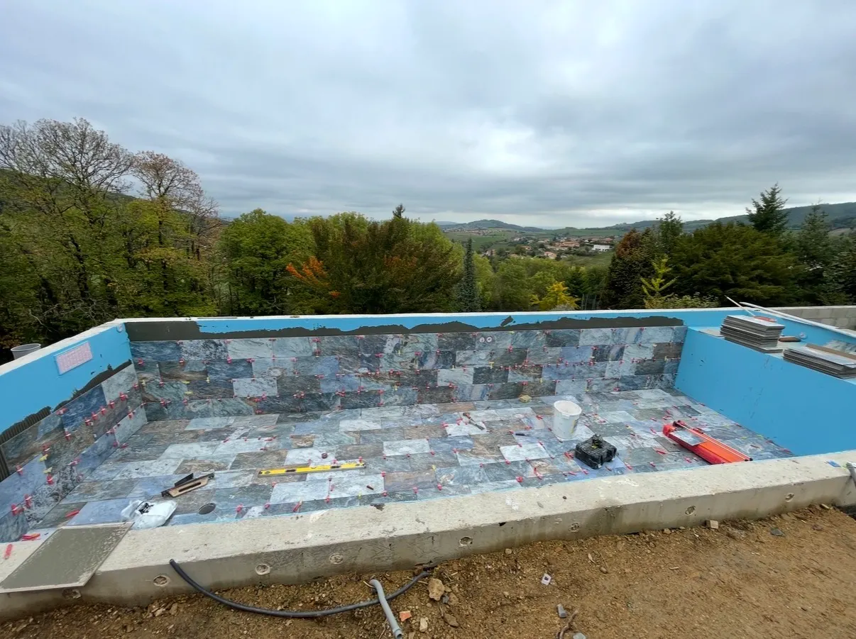 Pose de carreaux en pierre naturelle dans une piscine extérieure en cours de rénovation