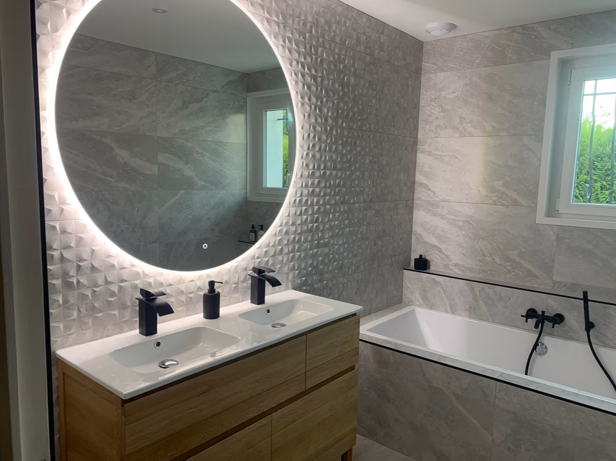 Salle de bain avec carrelage gris effet pierre, mur texturé, baignoire et meuble double vasque en bois
