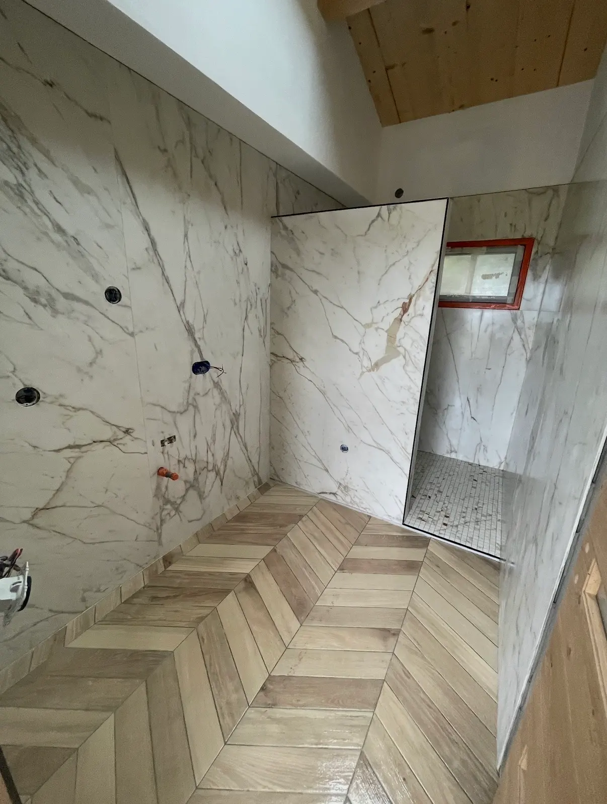 Salle de bain en cours de réalisation avec grands carreaux effet marbre et sol imitation bois en chevrons