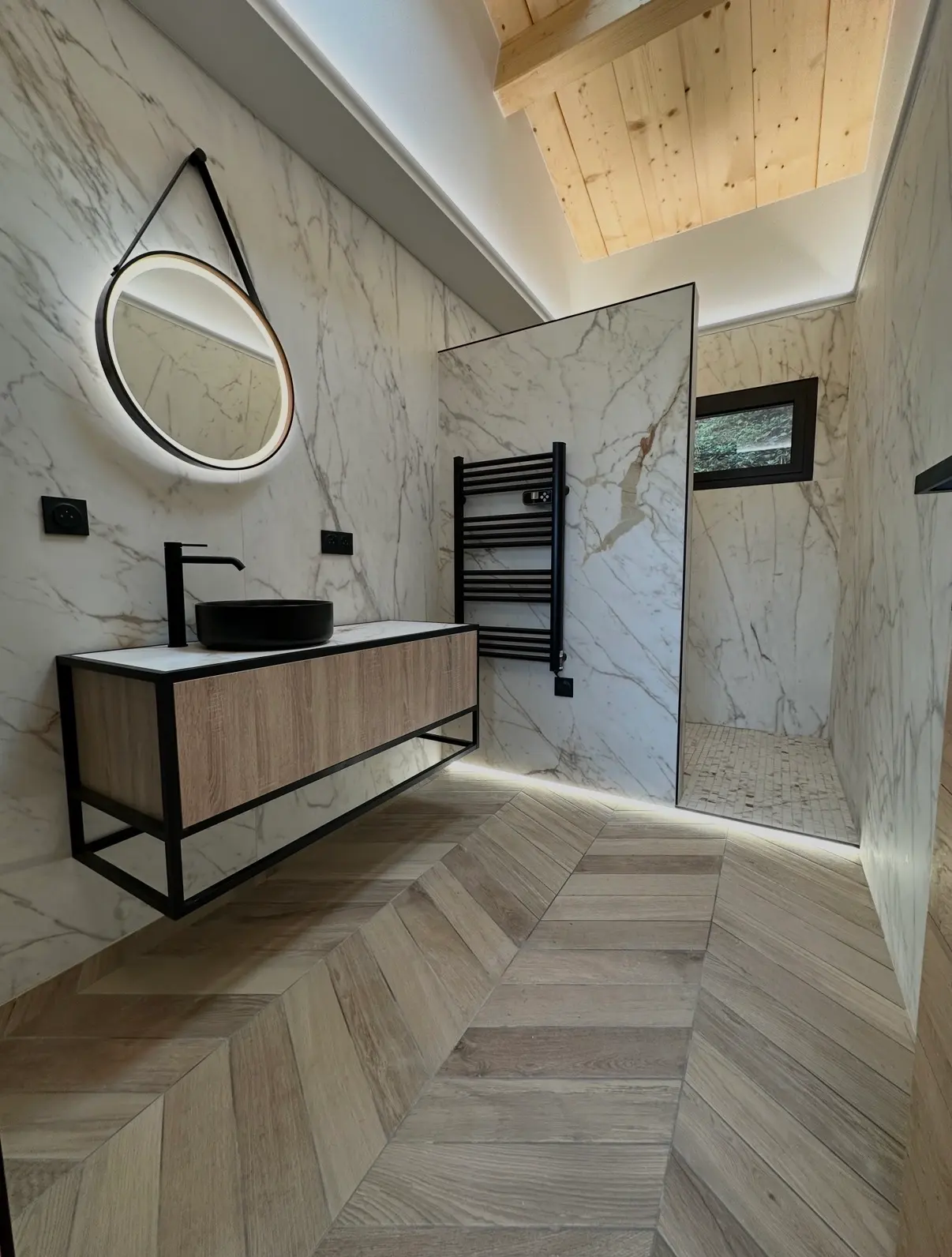 Salle de bain avec carrelage effet marbre et sol imitation bois posé en chevrons