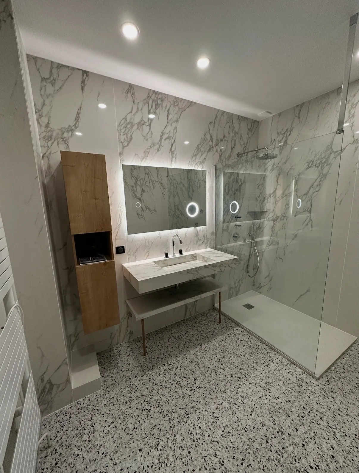 Salle de bain avec grands carreaux effet marbre aux murs et sol terrazzo