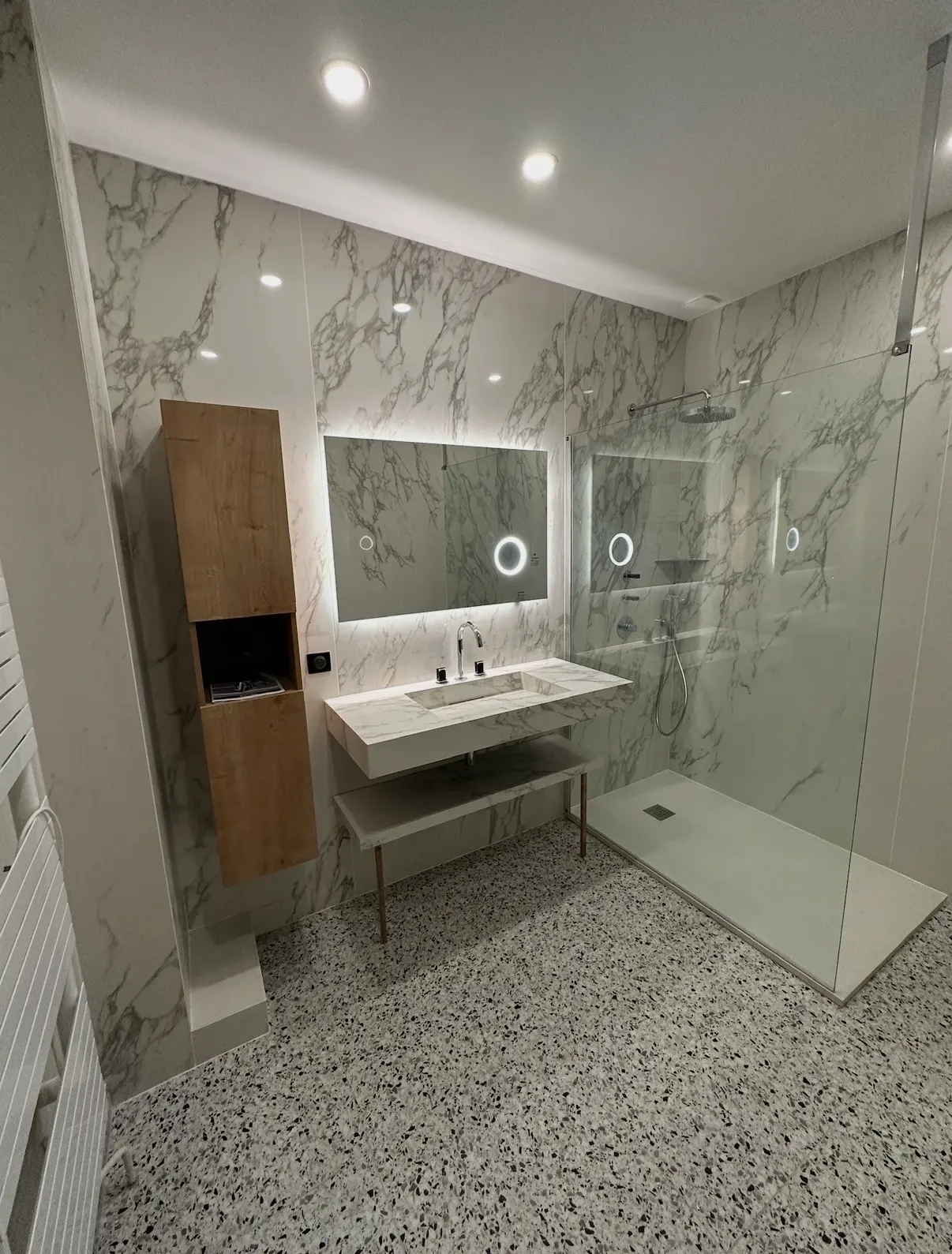 Salle de bain avec grands carreaux effet marbre aux murs et sol terrazzo