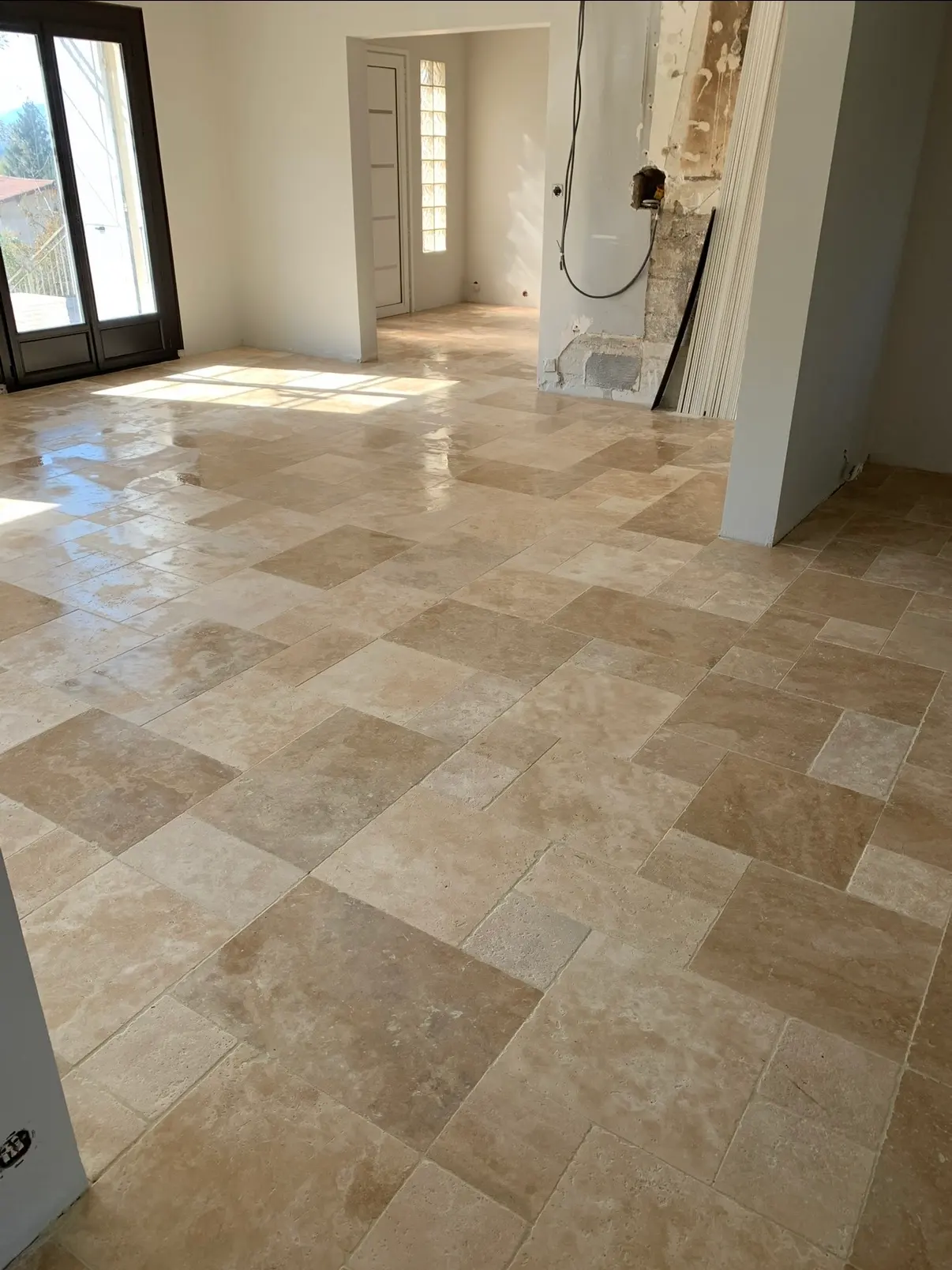 Sol intérieur en dalles de travertin beige dans une pièce lumineuse en rénovation