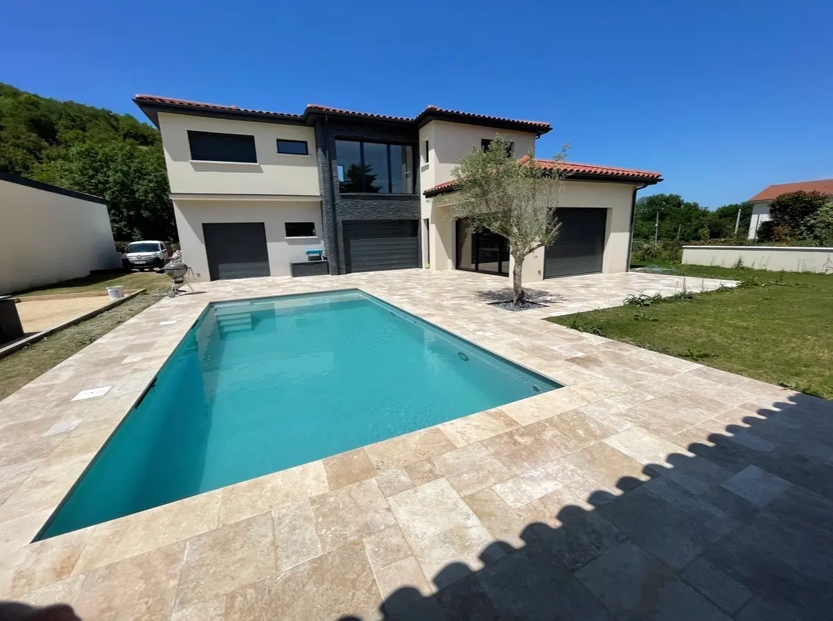 Piscine extérieure bordée d’une terrasse en dalles de pierre naturelle devant une maison contemporaine