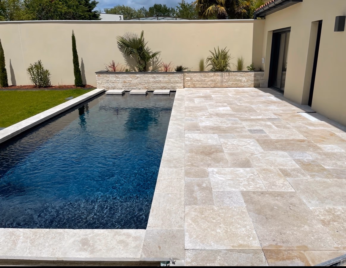 Terrasse en travertin clair autour d’une piscine contemporaine